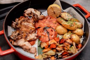 grilled chicken, grilled tomato and potatoes in a pot.