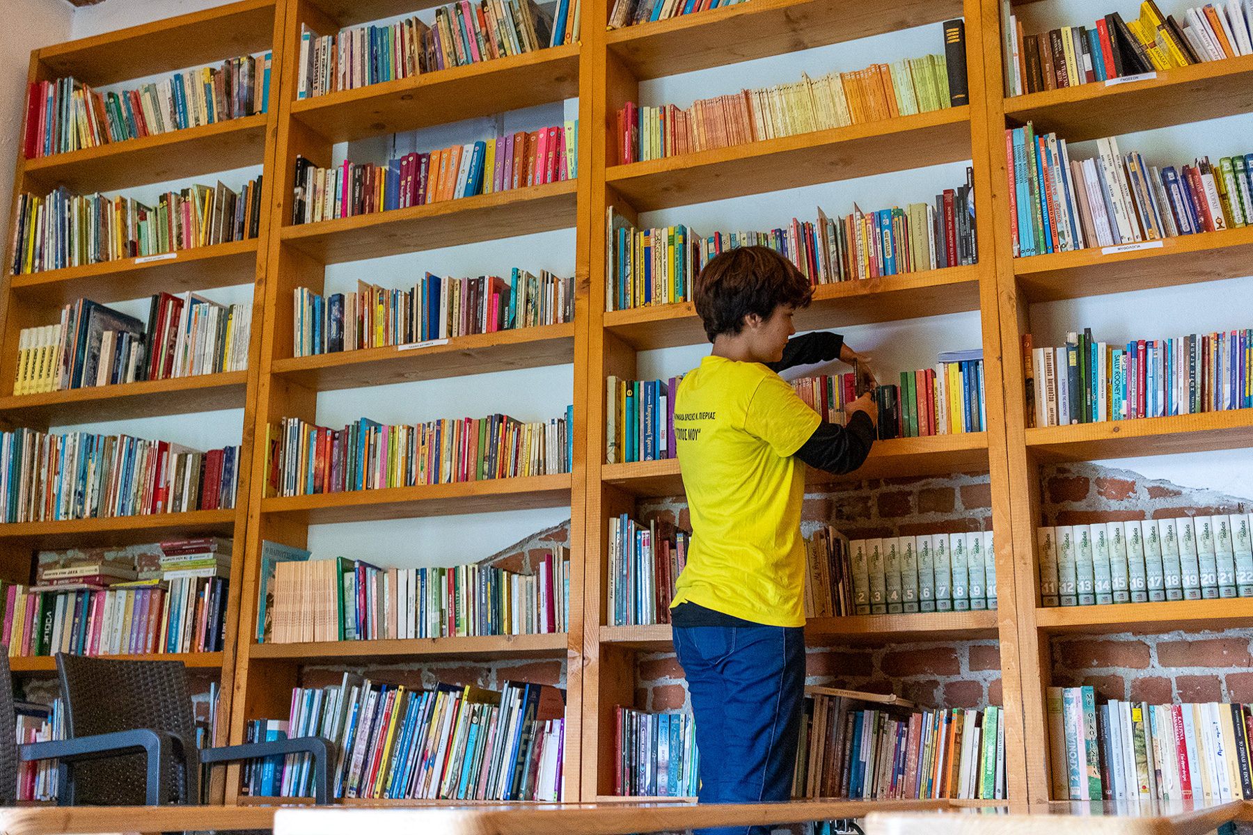 Anna choosing a book from the shared library in Kapnikos Stathmos, Katerini Pieria Greece