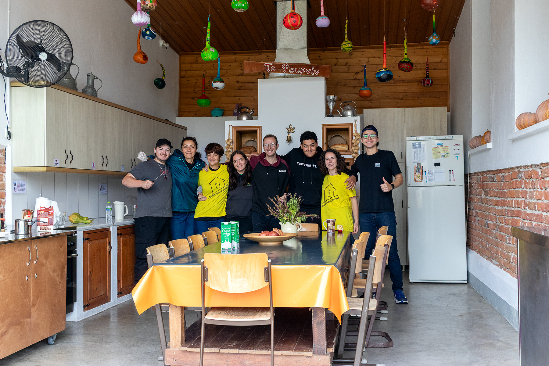 Volunteers gathered around the shared kitchen table at Kapnikos Stathmos, Katerini Pieria Greece