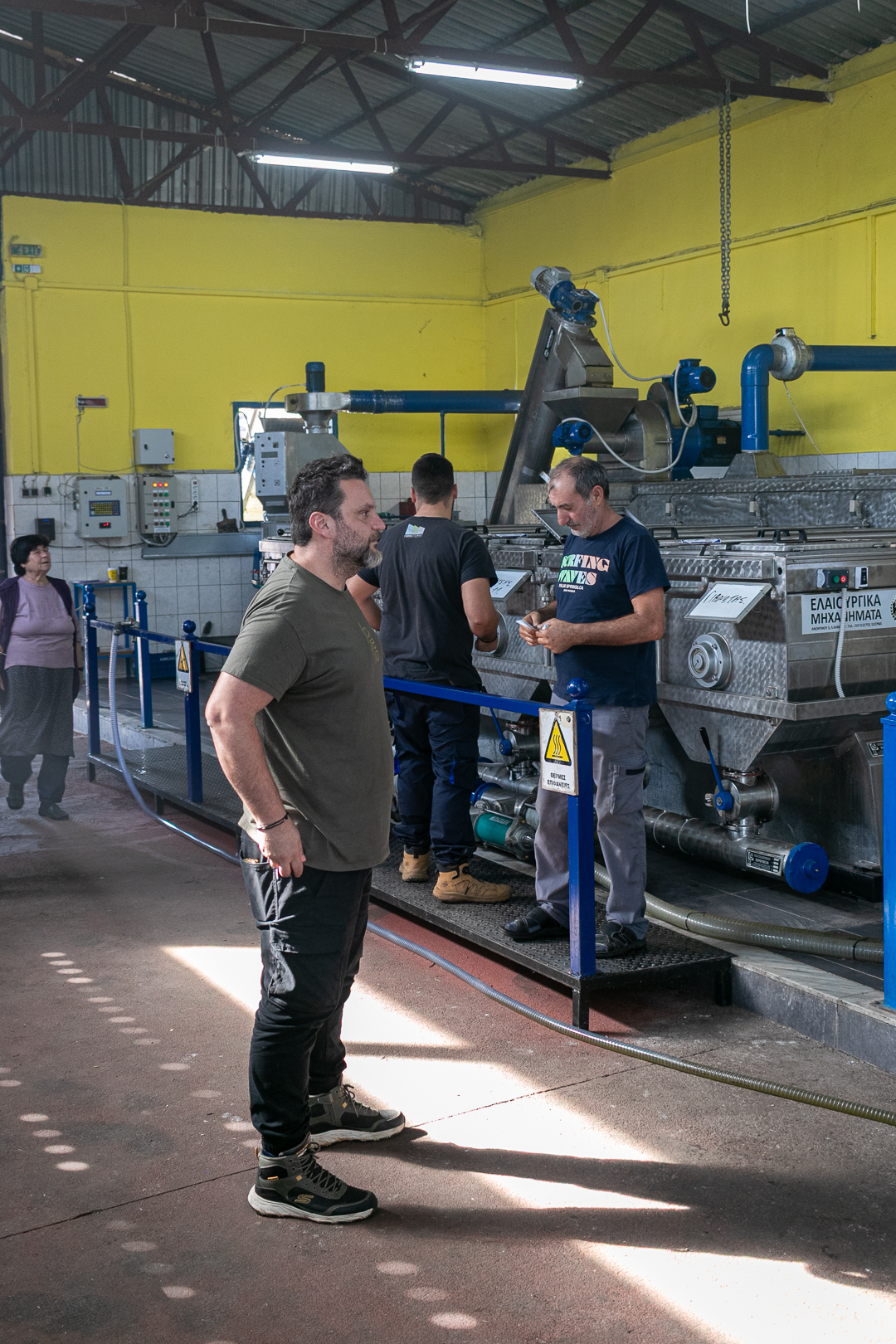Kostas Kapsalis, one of Forelia's two partners, standing beside processing machinery inside the olive oil mill.
