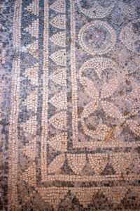 Overhead view of a geometric mosaic floor with circular and linear patterns at Louloudies, Pieria.