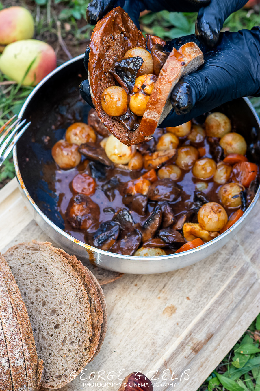 Rustic bread served with mushroom and vegetable bourguignon beside the pan during an outdoor meal on a private chestnut estate near Skotina, Pieria